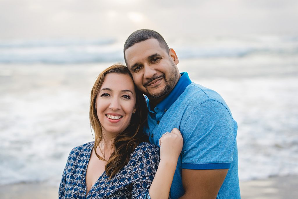 engaged couple smiling for the camera at Mission Beach San Diego