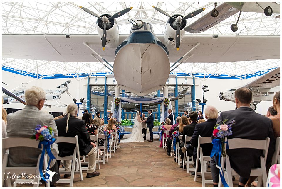 bride groom standing underneath airplane for air space museum wedding ceremony