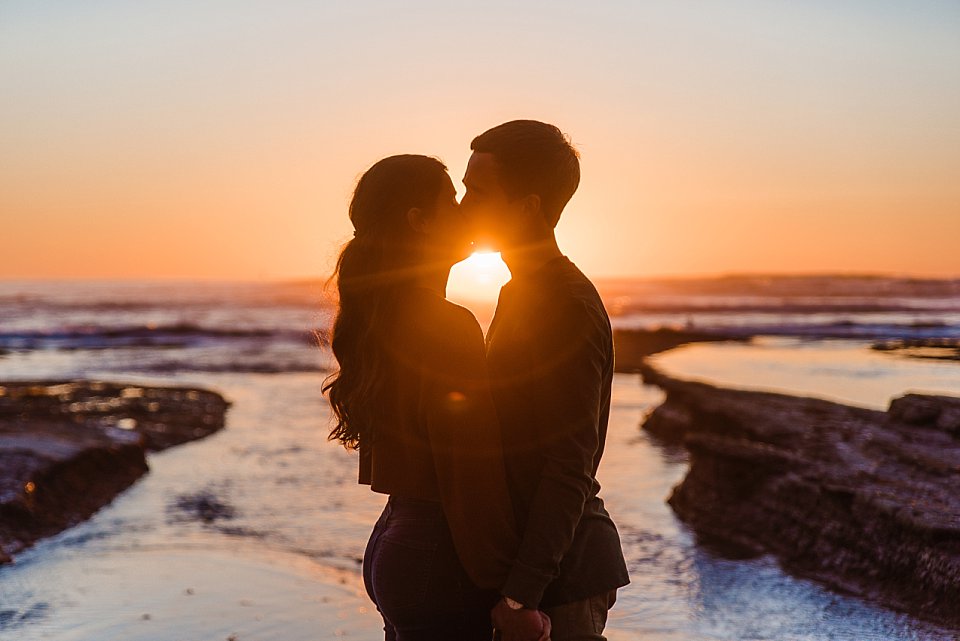 guy girl kissing in front of beach sunset san diego engagement photos