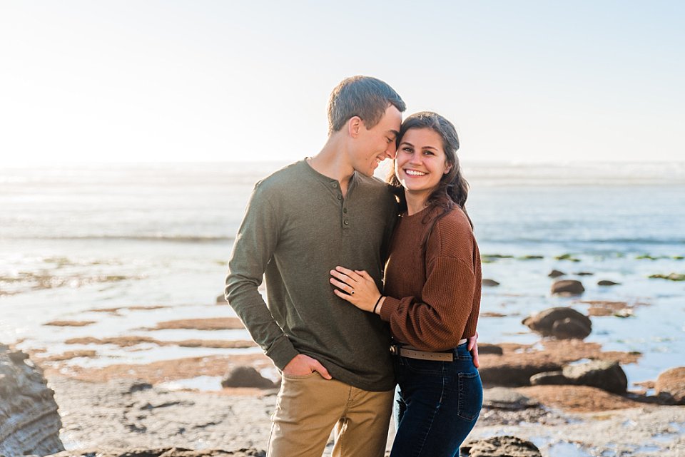 guy nuzzling closely while girl smiles san diego beach engagement photos
