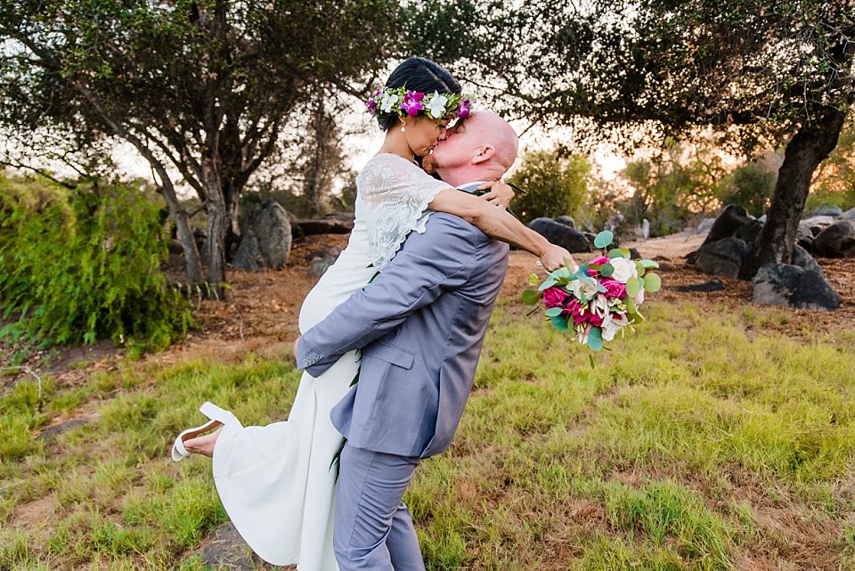 wide angle view of groom lifting kissing bride san diego park wedding