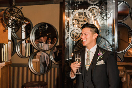 Groom laughing at groomsmen reflected in a mirror