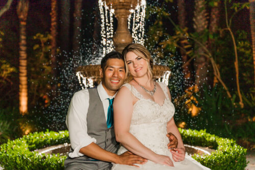 nighttime photo of bride and groom sitting in front of lit up waterfountain at grand tradition wedding venue