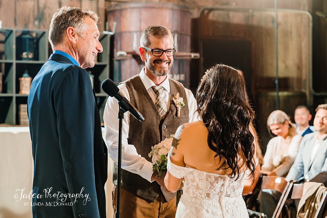 groom smiling at bride during ceremony in Barrel Room at Bernardo Winery