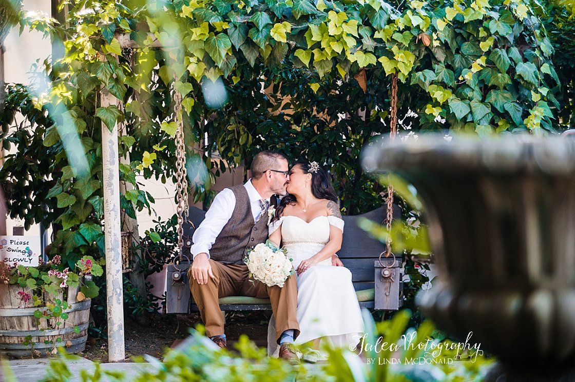 wedding couple kissing under swing and ivy at rustic wedding venue San Diego
