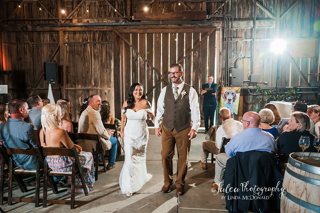 bride and groom walking down the aisle after saying I do at rustic wedding venue