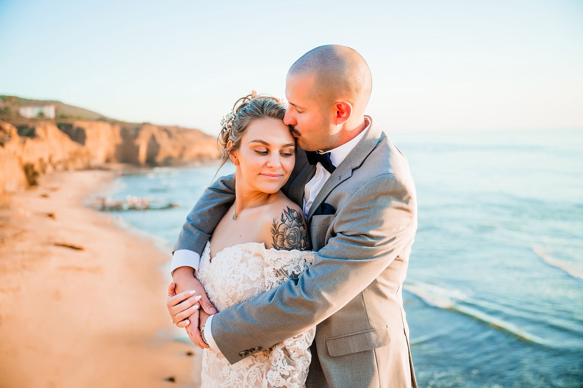 A couple in wedding attire in a romantic embrace along the edge of Sunset Cliffs in San Diego