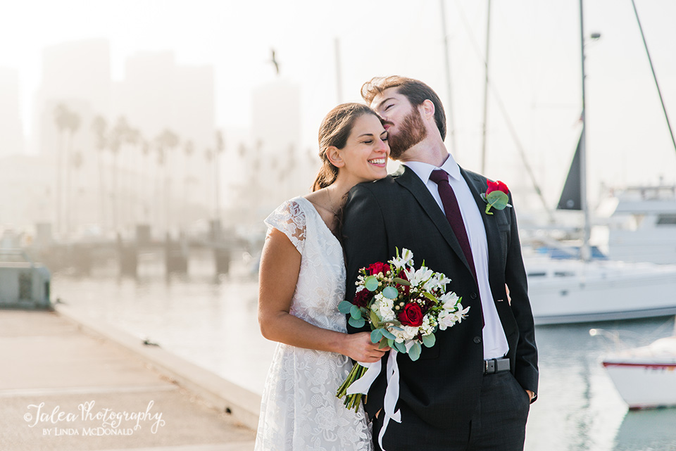 Playful bride and groom portrait in the early morning light by the San Diego harbor
