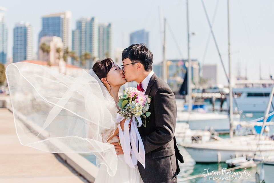 Bride and Groom share a kiss in front of the harbor after their San Diego courthouse wedding ceremony