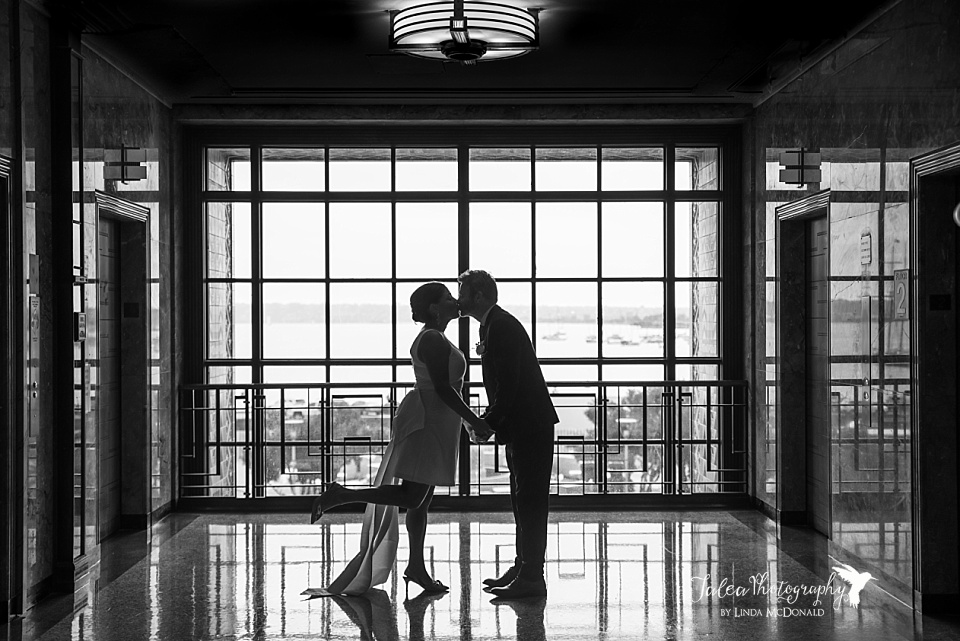 A couple poses in front of the window after their San Diego County Administration Center Wedding