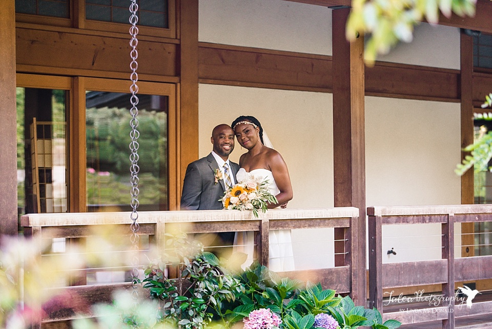 Black bride and groom pose on the deck of the Inamori Pavilion at Japanese Friendship Garden San Diego